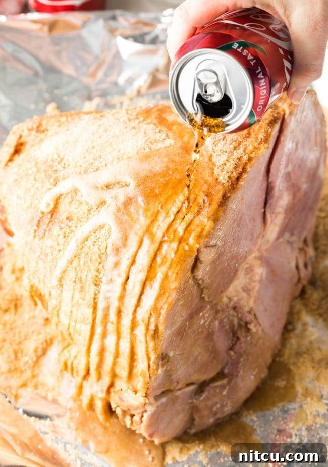 Coca-Cola Uncut 6 A hand gently pours a can of Coca-Cola over the ham, ensuring it coats all surfaces before the baking process begins.