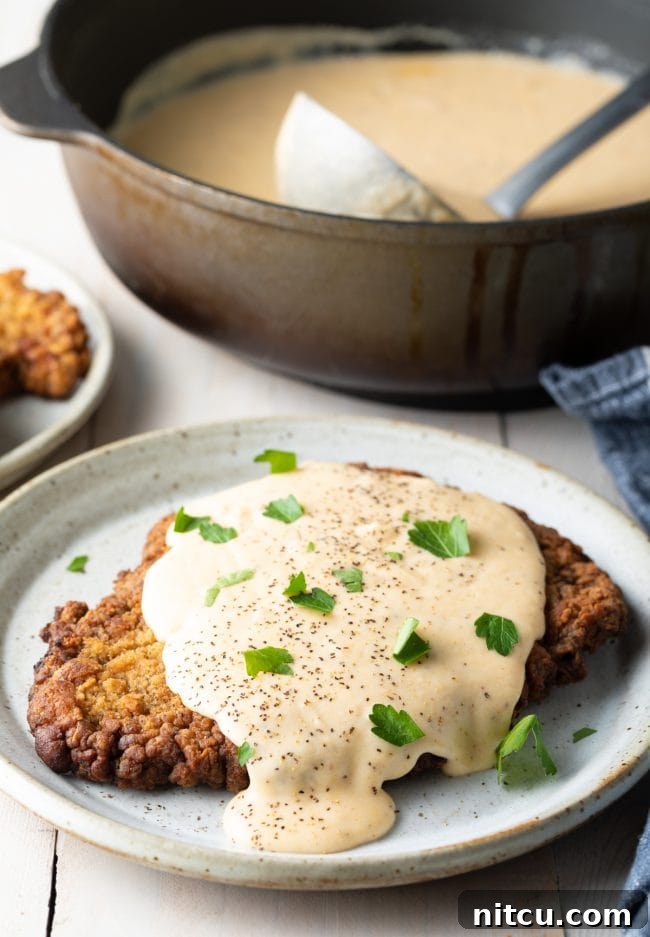 Effortless Chicken Fried Steak 9 Chicken Fried Steak recipe: A perfectly plated chicken fried steak, generously smothered in white gravy, presented beautifully on a rustic dinner setting.