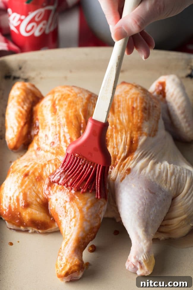 Coca Cola Glazed Spatchcock Chicken 7 Spreading coca cola sauce across spatchcock chicken before roasting.