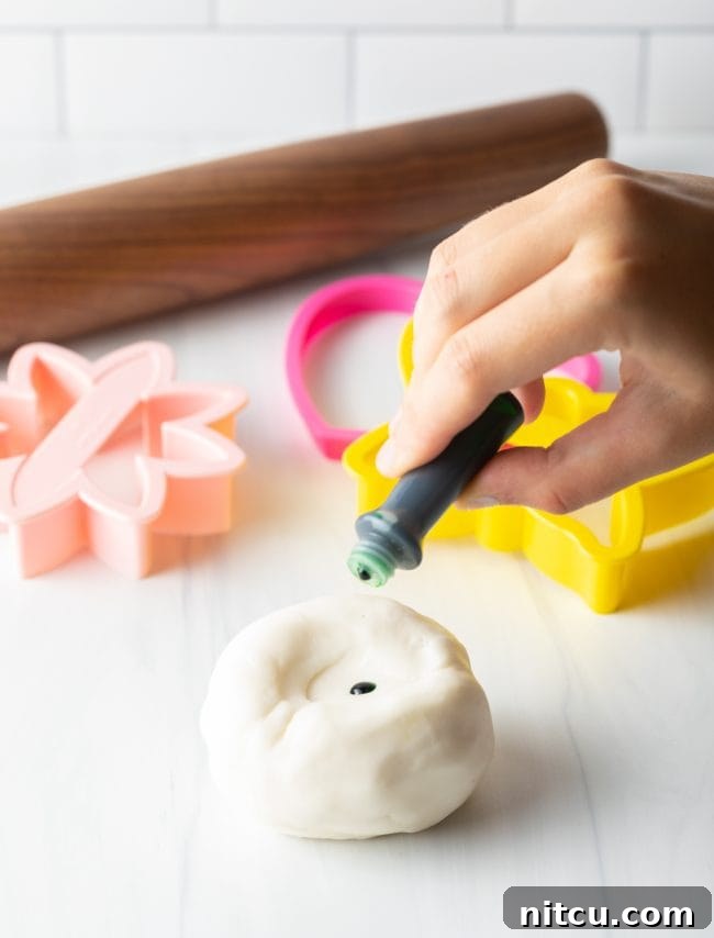 Easy Homemade Fondant 8 Hand adding food coloring to homemade fondant.