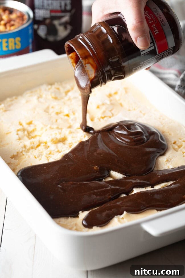 The Ultimate Peanut Butter Chocolate Ice Cream Cake 8 Hot fudge sauce being poured over the first ice cream layer.