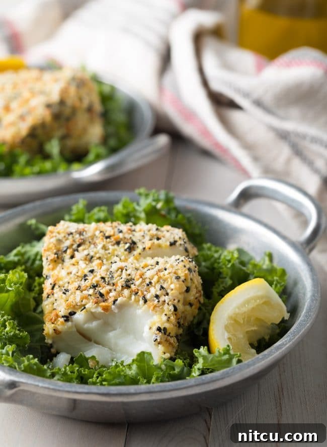 Everything Bagel Crusted Cod 4 Cod with an everything bagel seasoning crust with some of it flaked off to show the inside of the fish.