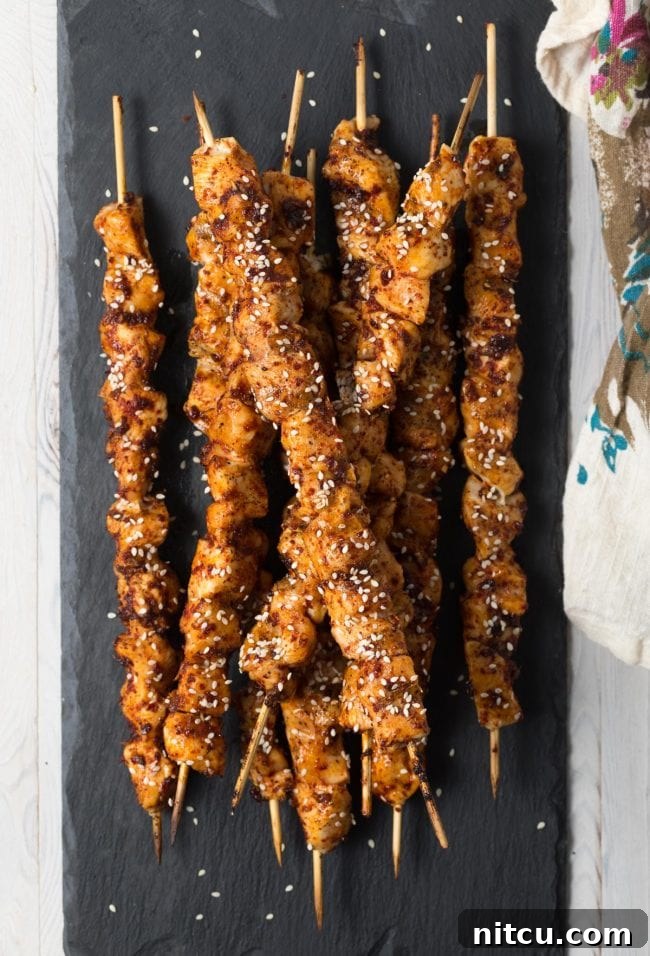 Gochujang Glazed Chicken Skewers 2 Delicious Low Carb Korean Chicken Skewers on a grill, garnished with sesame seeds.