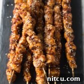 Korean Chicken Skewers Recipe on a wooden board with sauce.