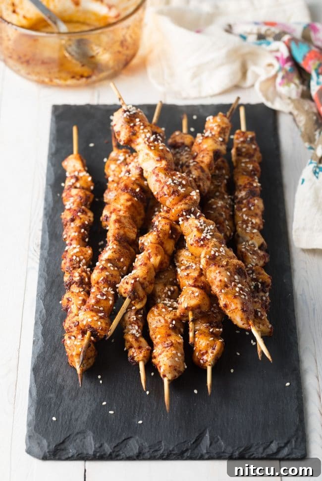 Gochujang Glazed Chicken Skewers 8 A plate of freshly grilled Korean chicken skewers, garnished with sesame seeds.