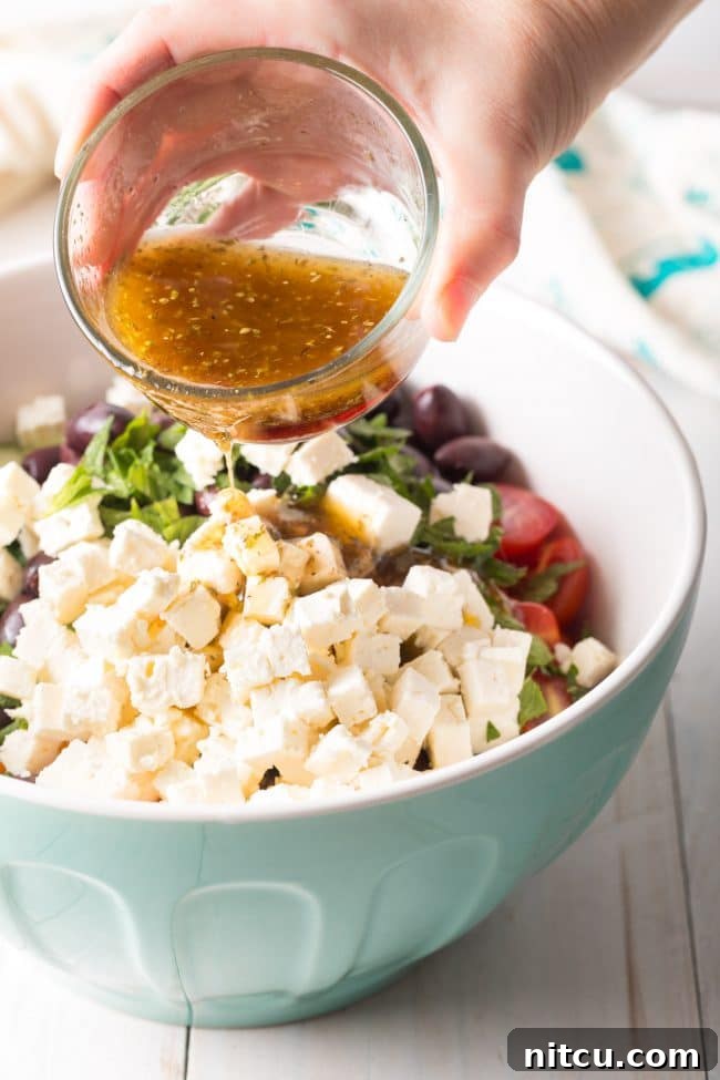 Horiatiki Greek Village Salad 8 Best Greek Horiatiki (Village Salad) Recipe showing the dressing being poured over the salad. #greek #salad #glutenfree #lowcarb #keto #vegetarian