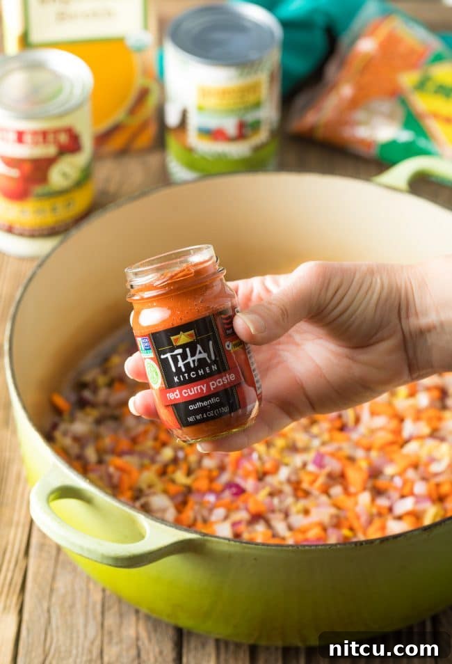 Spiced Red Lentil Bliss 6 Hand holding jar of Thai Red Curry Paste to camera.