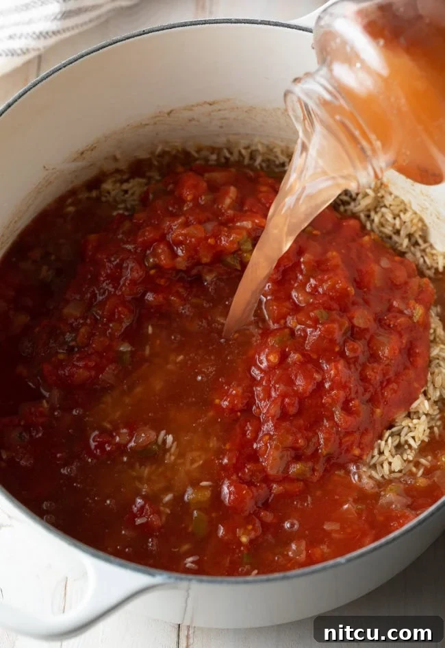 Effortless Spanish Rice 7 Water being poured from the salsa jar into the pot of rice and salsa, illustrating how to get all the residual flavor and ensure proper liquid measurement. This step is part of the 'incorporate the salsa and liquid' instruction, ensuring all ingredients are combined for cooking.
