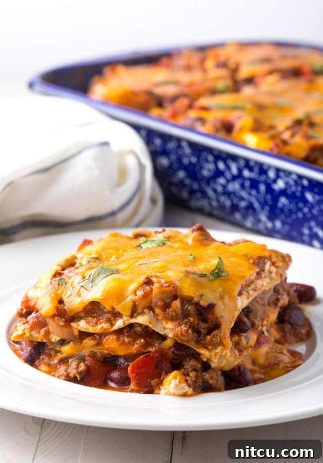 Hearty Cowboy Chili Lasagna layered in a casserole dish, ready to be baked with noodles, chili, and cheese visible