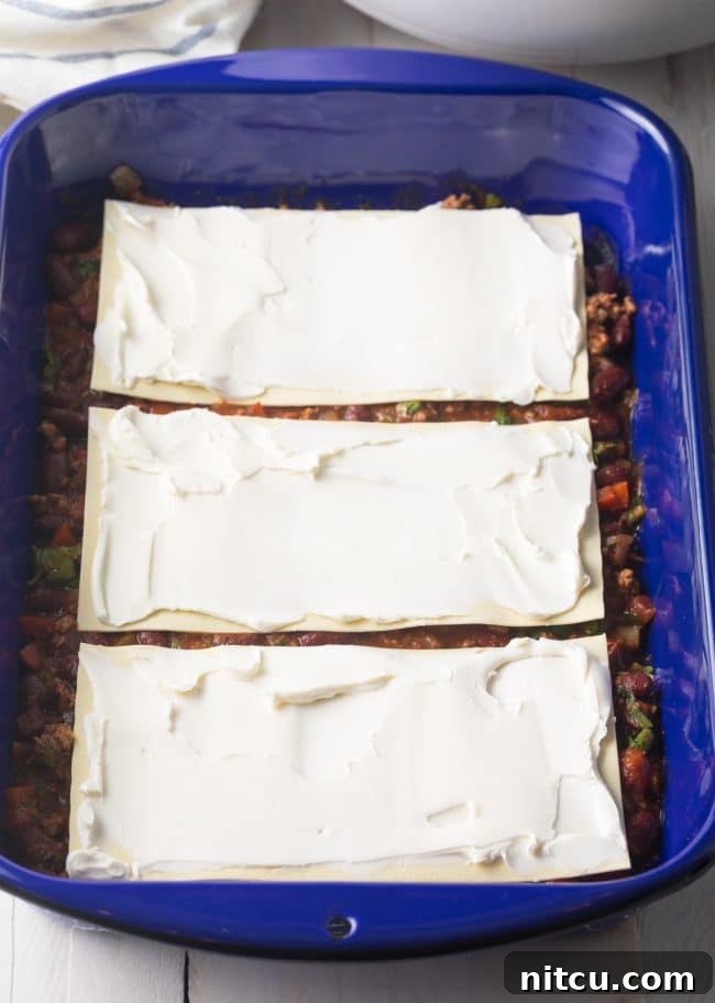 First layer of Cowboy Chili Lasagna assembly, spreading a base of chili over the pan