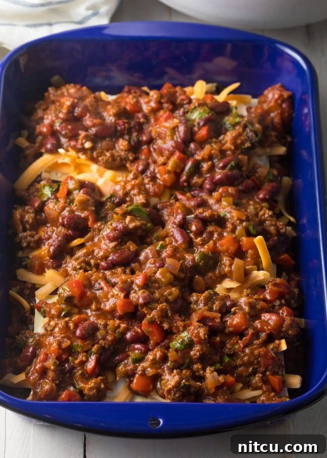 Third layer of Cowboy Chili Lasagna, carefully spreading the hearty chili mixture over the noodles and cheese