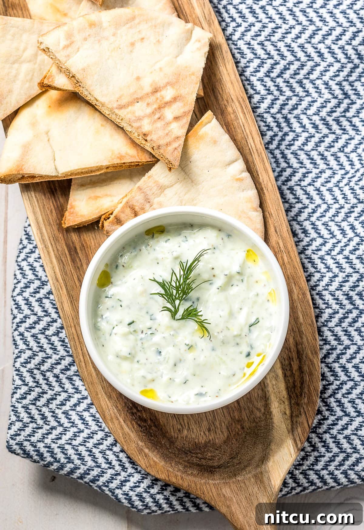 Refreshing Greek Cucumber Dip 2 Tzatziki dip in a white bowl, placed on a wood platter with pita bread.