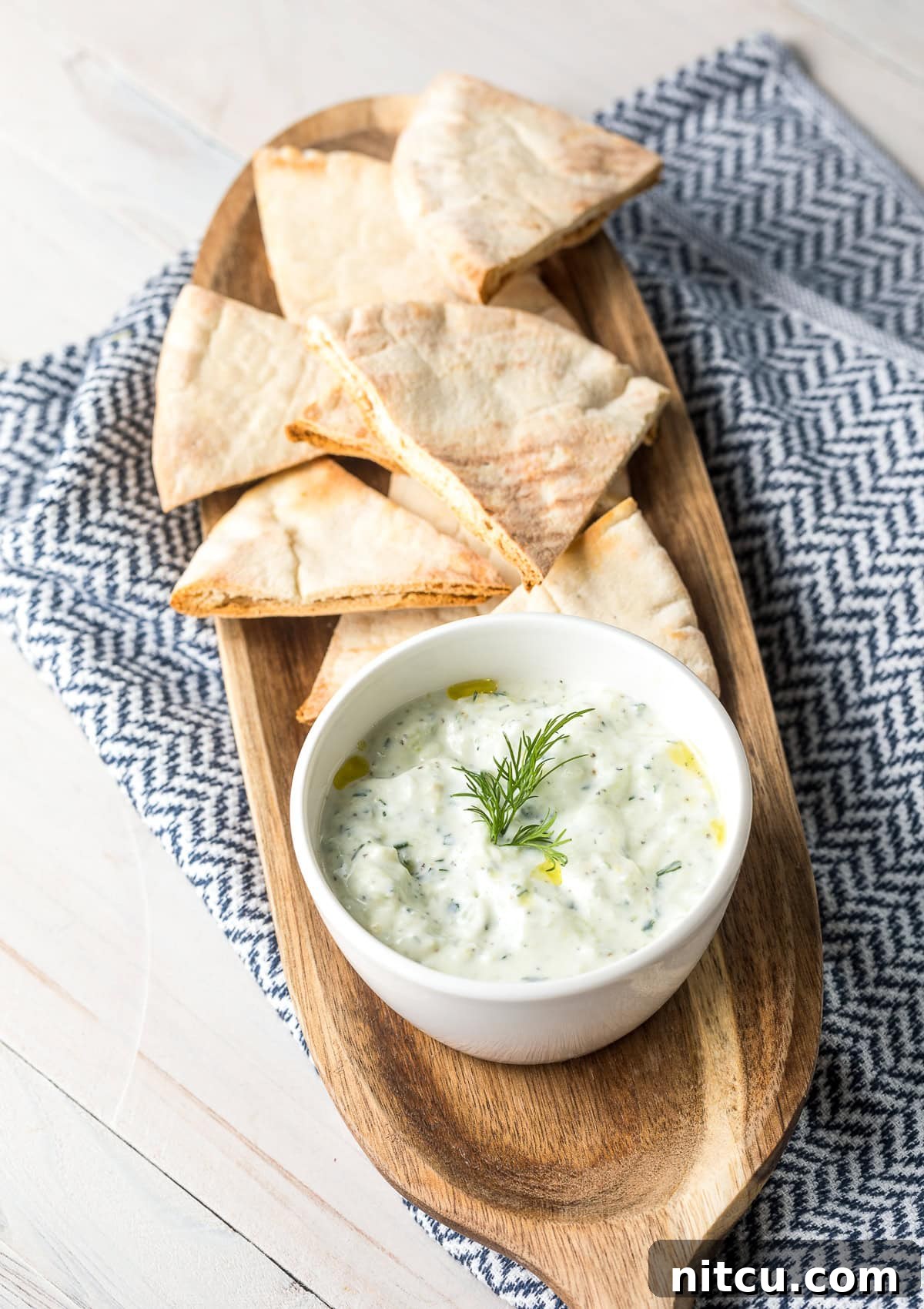 Refreshing Greek Cucumber Dip 8 Tzatziki dip in a white bowl, placed on a wood platter with pita bread.