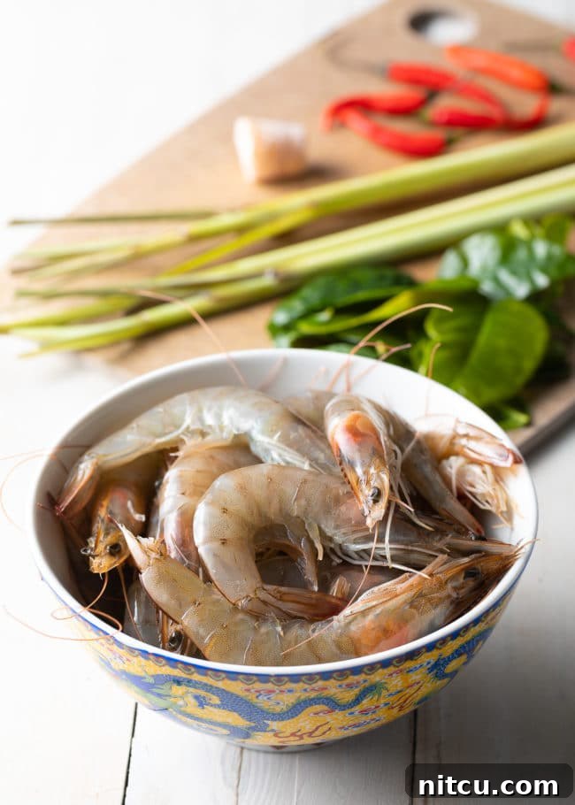 Spicy Thai Tom Yum Soup 5 A bowl of raw shrimp arranged with fresh lemongrass, kaffir lime leaves, and other essential Tom Yum soup ingredients, ready for preparation.