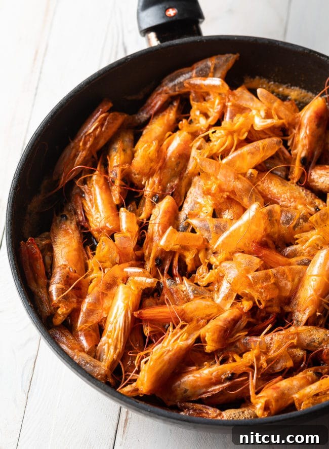 Spicy Thai Tom Yum Soup 7 Shrimp heads are sautéing in a skillet with oil, turning red and crispy to create flavorful shrimp oil for the Tom Yum soup.