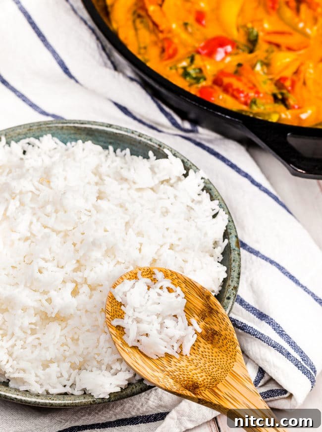 A wooden spoon holding rice over a bowl of basmati rice.