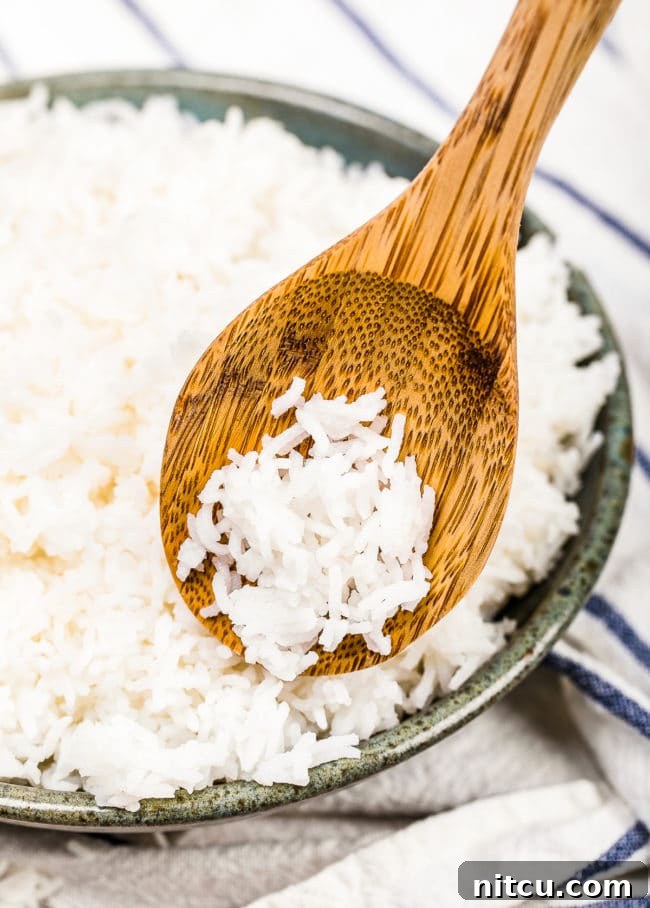 Basmati Rice Cooking - A wooden spoon holding rice over a bowl of basmati rice.