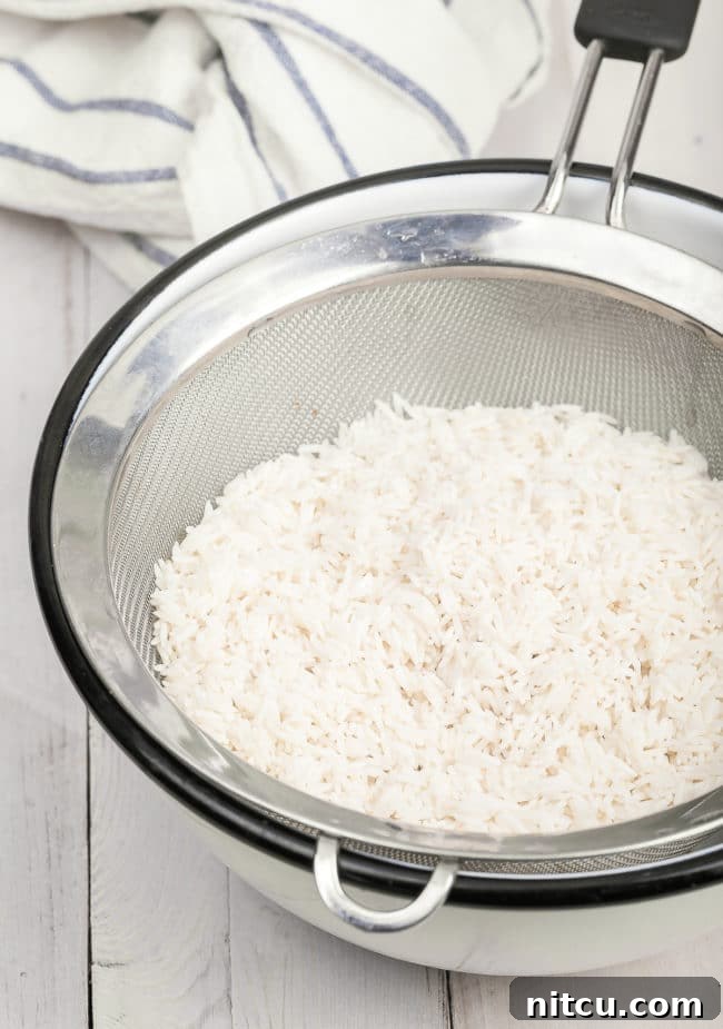 Basmati rice in a sieve set over a bowl.