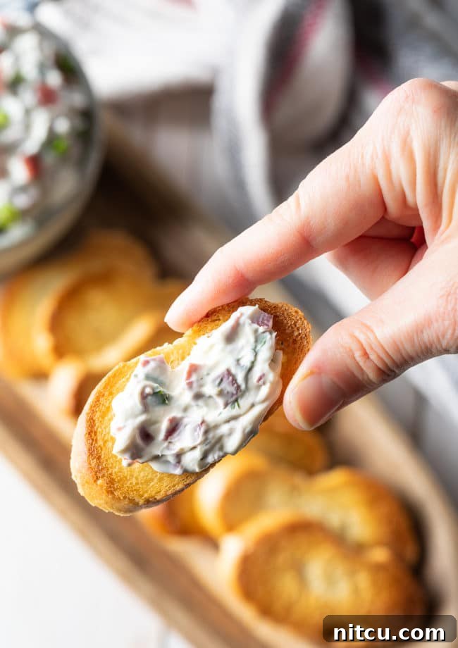 Hand holding up a crostini with chipped beef dip. 