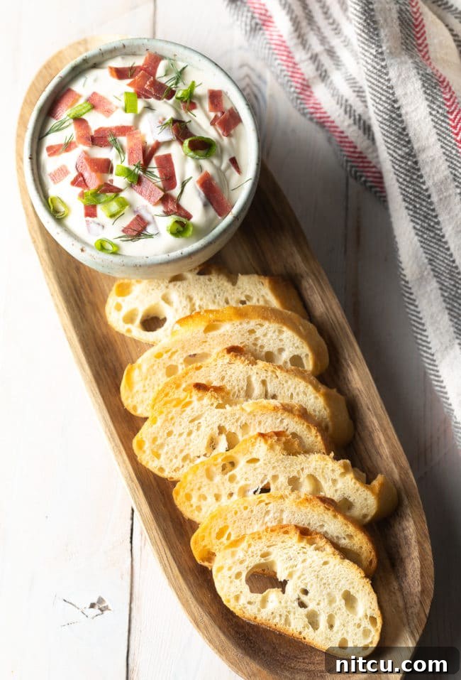 Dried beef dip in a small bowl with toasted bread next to it. 