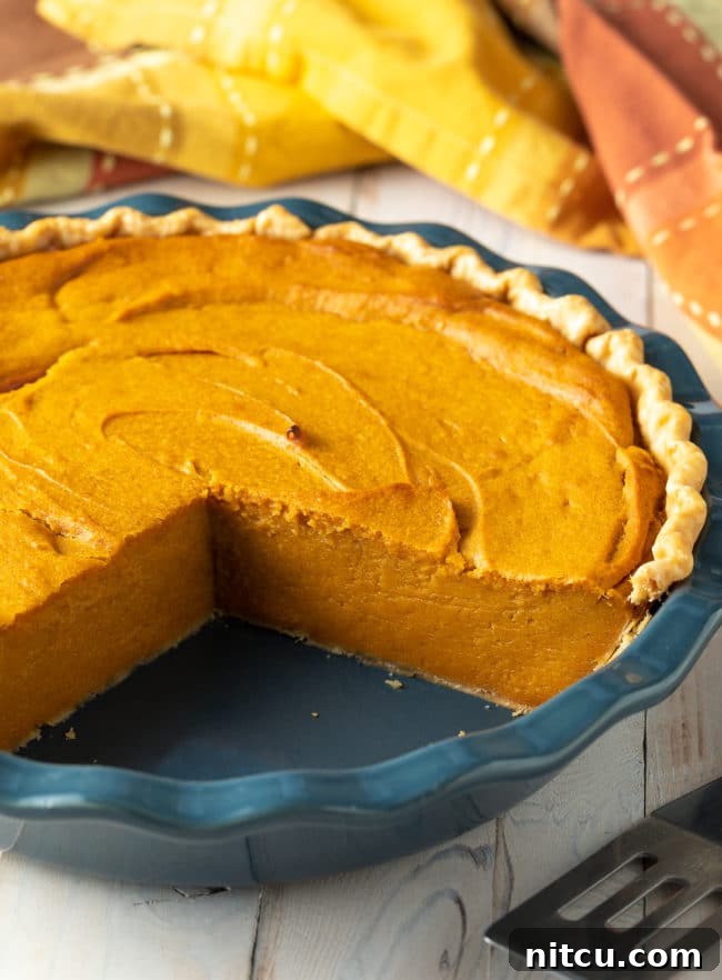 best-pie A whole, easy-to-make sweet potato pie with several slices already removed, revealing its creamy golden interior and inviting texture. It sits on a rustic wooden surface, highlighting its homemade appeal.