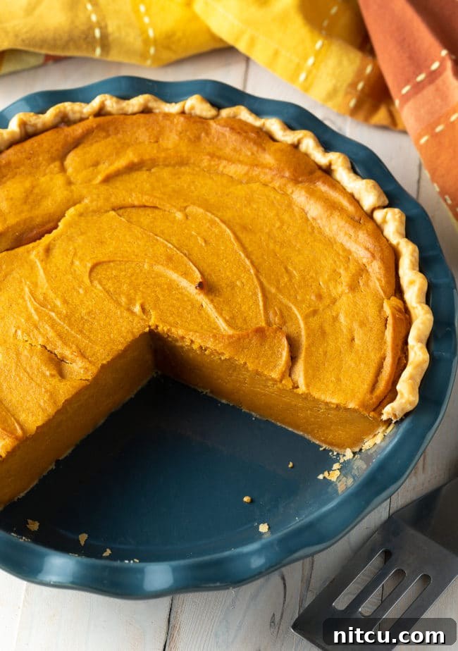 Velvety Southern Sweet Potato Pie Perfection 4 An easy-to-make sweet potato pie, freshly baked, with a few slices removed to show its appealing texture and readiness for serving during a festive meal.