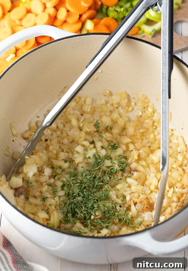 Fragrant onions, minced garlic, and fresh thyme sautéing in a hot pot, building a flavorful base.