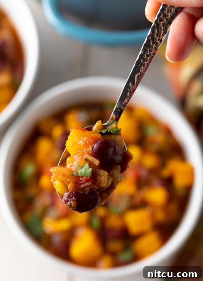 Hearty Butternut Chili 12 A close-up of a spoonful of crock pot butternut squash chili, highlighting its vibrant colors and rich texture.