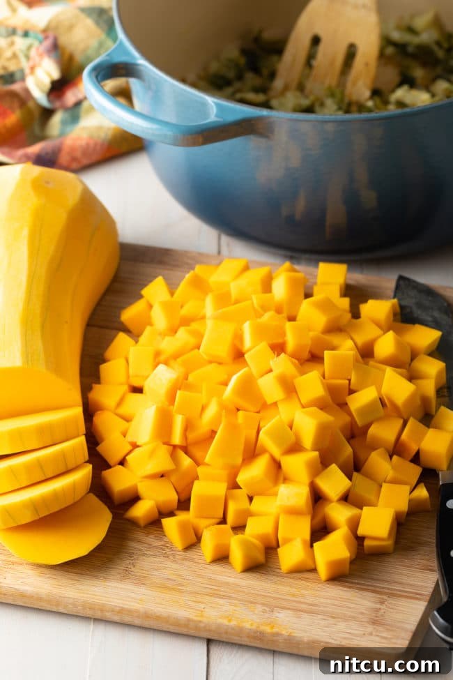Hearty Butternut Chili 5 Freshly peeled and diced butternut squash cubes on a wooden cutting board, ready for cooking.