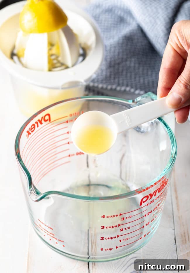 Whipping Up Buttermilk At Home 5 A glass measuring cup as a hand pours lemon juice into the milk.