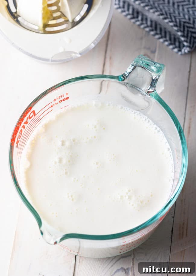 Whipping Up Buttermilk At Home 7 Homemade buttermilk substitute actively curdling in a clear glass measuring cup, showing the thickening process.