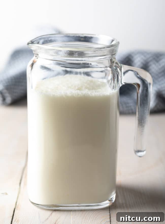 Whipping Up Buttermilk At Home 8 A beautiful side view of a small glass pitcher, perfectly filled with fresh homemade buttermilk.