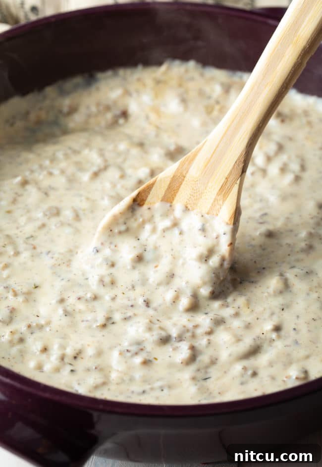 Effortless Homemade Sausage Gravy 2 Easy sausage gravy in a pan with a wooden spoon.