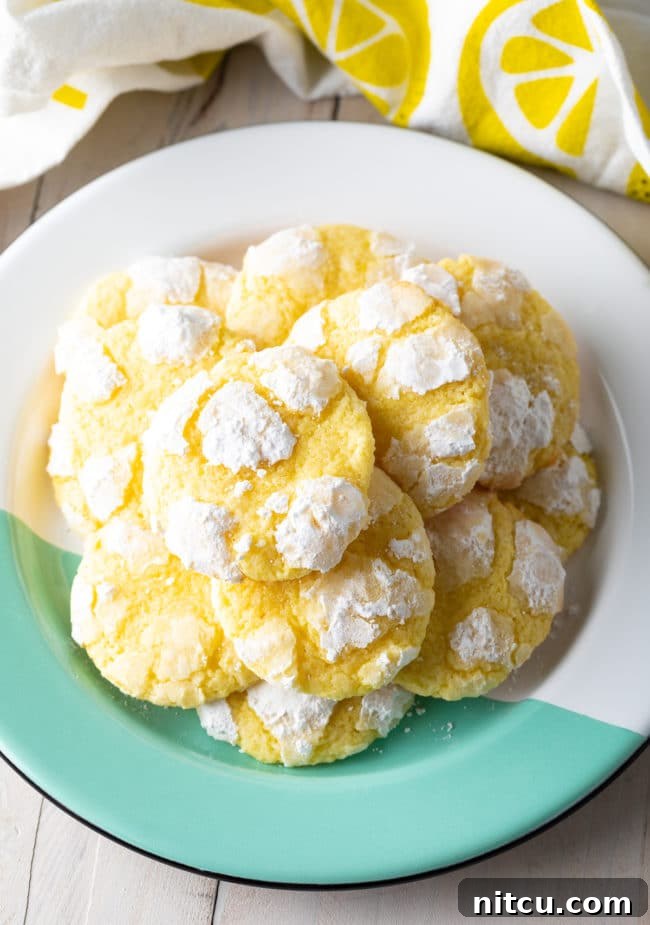 Zesty Lemon Crinkles 2 A stunning overhead shot showcasing a plate filled with perfectly stacked, powdery Lemon Crinkle Cookies, ready to be enjoyed.