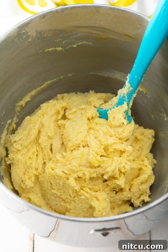 Zesty Lemon Crinkles 6 A mixing bowl filled with freshly prepared Lemon Crinkle Cookie dough, showing its smooth, yellow consistency.