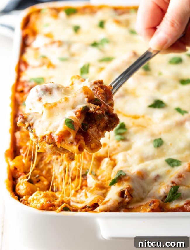 baked-ziti-with-ricotta-and-sausage baked ziti with sausage and ricotta spooned up from dish, highlighting the cheesy layers