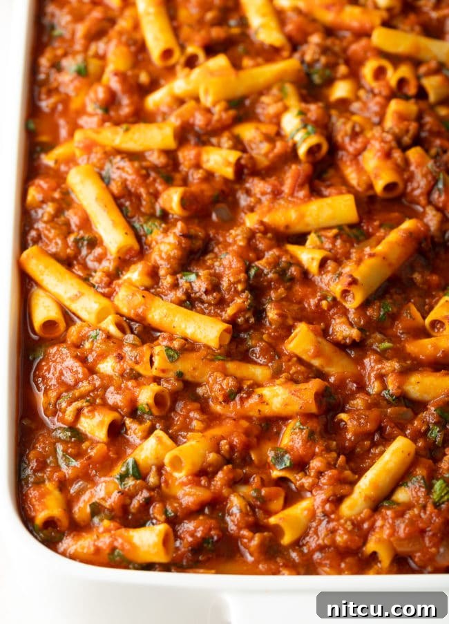 pasta-dinner-prep ziti, sauce, sausage, and cheese in baking dish, ready for the oven