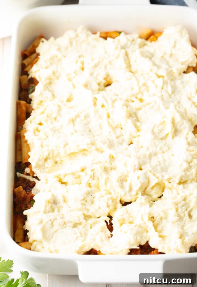 Hearty Italian Sausage Ziti Bake 2 Ricotta Filling on top of ziti - Baked Ziti with Sausage Recipe, showing the layering process