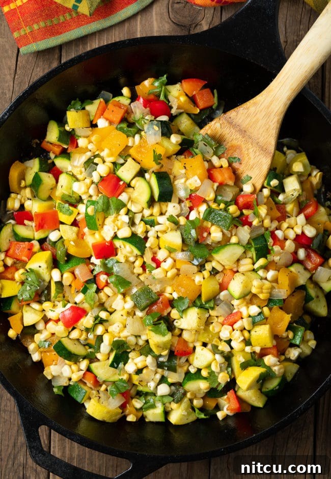 Mexican Calabacitas recipe in a large cast iron skillet with a wooden spoon, showcasing the delicious cooked vegetables.