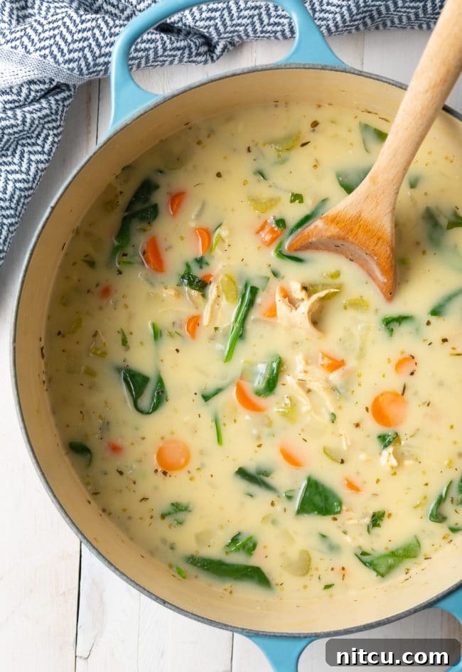 A rustic Dutch oven filled with simmering creamy lemon chicken and spinach soup, ready to be served.