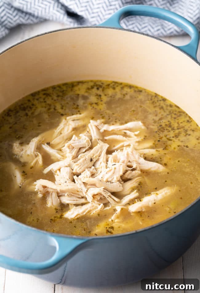 Step-by-step: Shredding cooked chicken on a cutting board, preparing it for the creamy lemon soup.