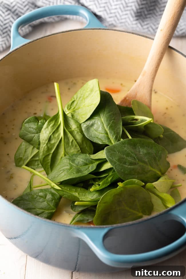 Garnishing creamy lemon chicken soup with fresh parsley and a lemon slice.