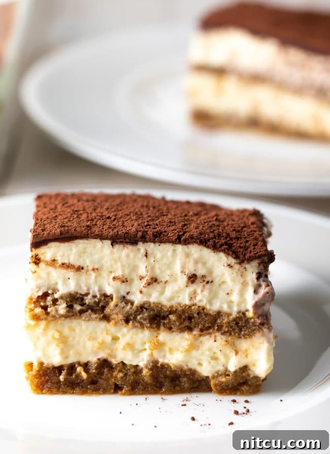 Espresso Pick-Me-Up Delight 5 A beautiful slice of easy tiramisu cake on a white plate, showcasing its fluffy cream and soft ladyfinger layers.