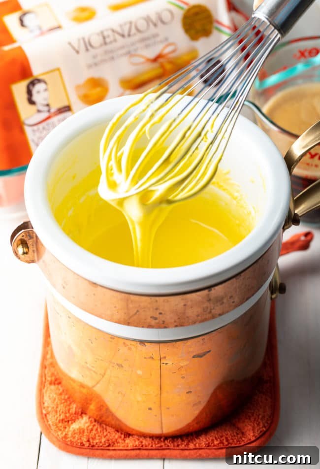 Espresso Pick-Me-Up Delight 7 A whisk vigorously mixing egg yolks and sugar in a bowl over a double boiler, creating the silky smooth sabayon for the tiramisu cream.