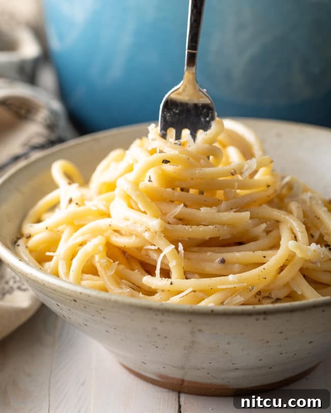 The Best Cacio e Pepe Recipe swirled enticingly on a fork, ready to be eaten.