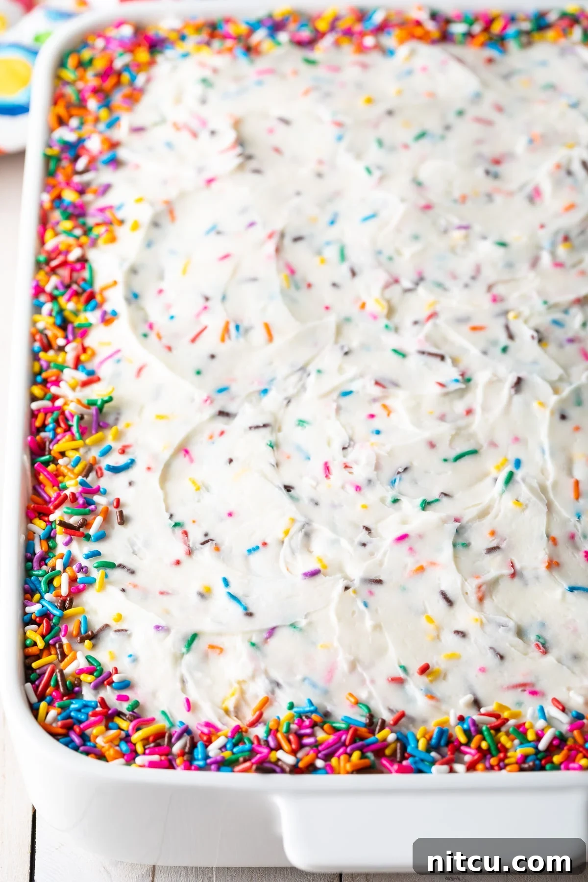 Fluffy Vanilla Cake From Scratch 4 Vanilla birthday cake in a baking dish adorned with colorful sprinkles around the edges.