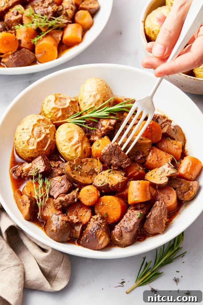venison-stew.jpg Venison Stew Recipe in a white bowl with a side of potatoes.