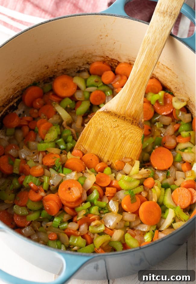 Nana's Masterpiece Chicken and Rice 8 Sauteed vegetables (onions, carrots, celery, garlic) softening in a pot, creating an aromatic base.