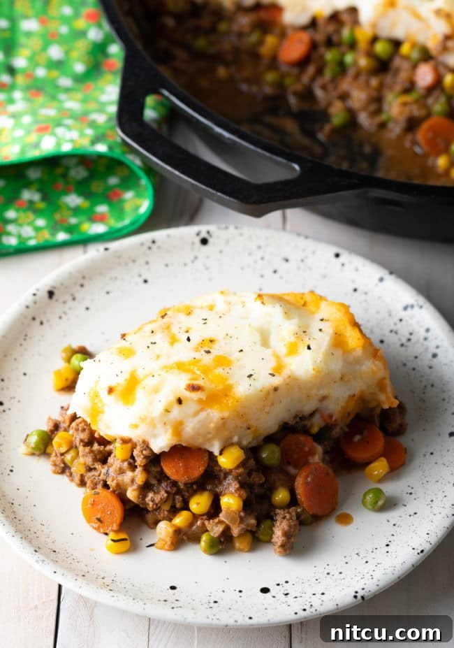 Two plates of Irish Cottage Pie with beef, one in the foreground and a second blurred in the background, ready to be enjoyed.