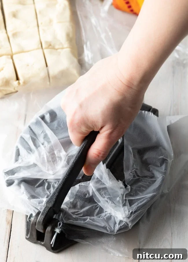 A hand firmly pressing down on the lever of a tortilla press, flattening the masa dough into a thin, perfectly round tortilla.